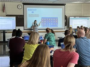 a teacher points to an electronic display as she talks to teachers